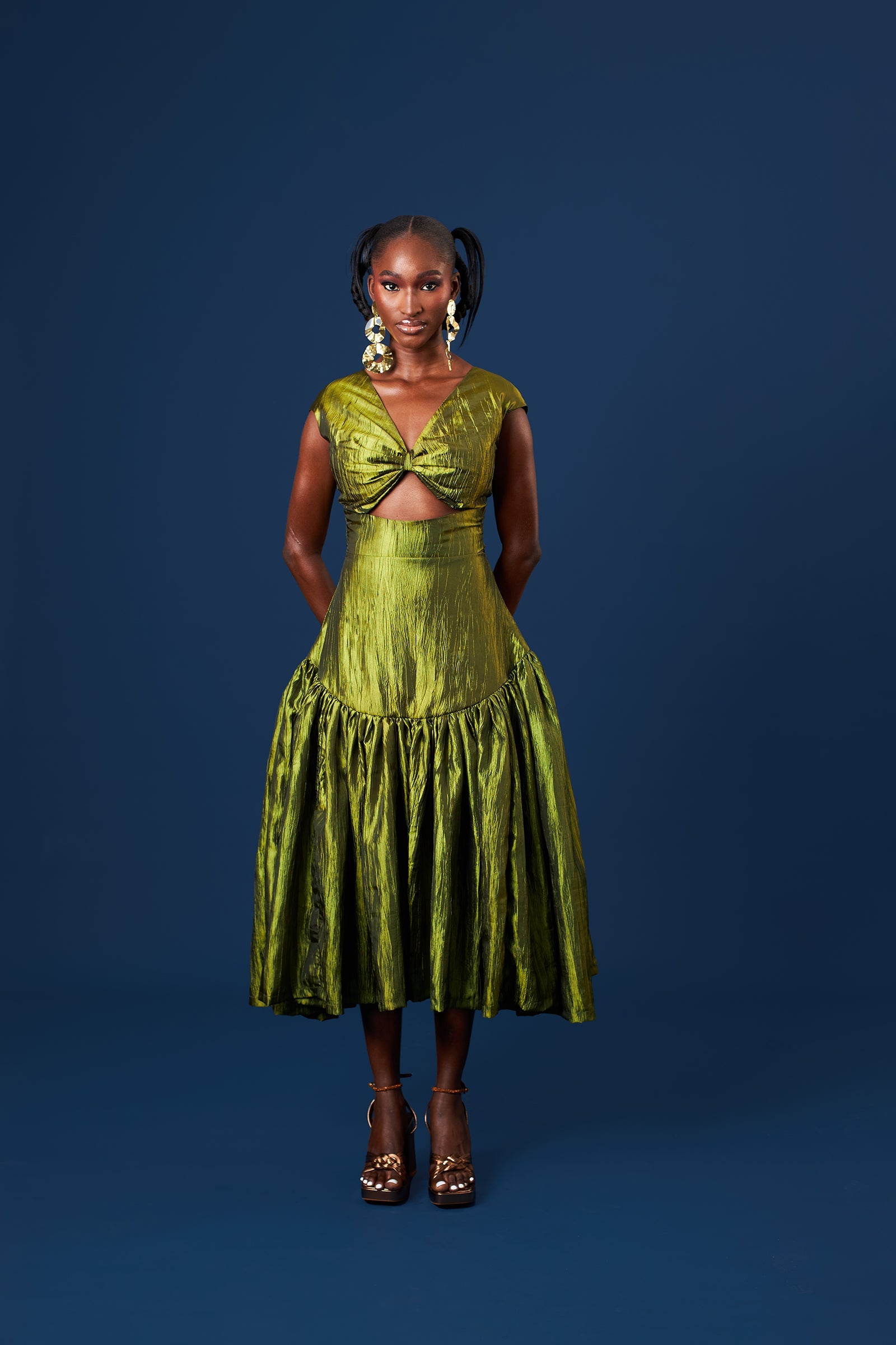 Woman wearing a green dress with cut-out details on a blue background